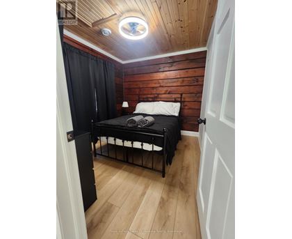 A bedroom with a bed, wooden walls, and a skylight.