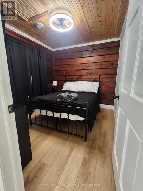 A bedroom with a bed, wooden walls, and a skylight.