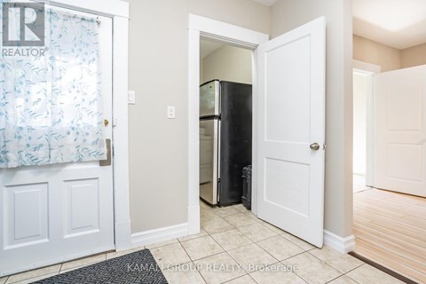 A room with a doorway leading to a darker room and a mat on the floor.