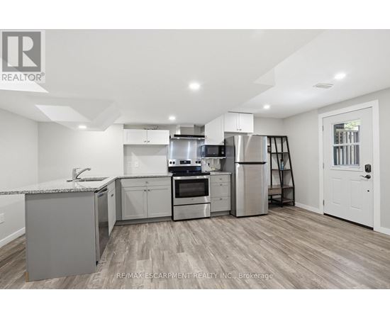 A modern kitchen with stainless steel appliances and wooden flooring.