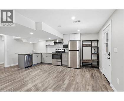 A well-lit kitchen with stainless steel appliances and wooden flooring.