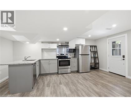 A modern kitchen with stainless steel appliances and wooden flooring.