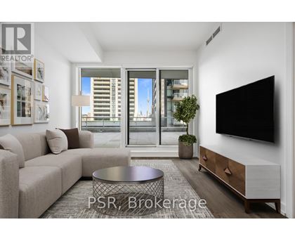 A living room with a couch, a coffee table, and a flat screen TV mounted on the wall.