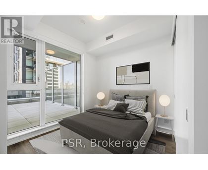 A bedroom with a large bed and a glass door leading to a balcony.