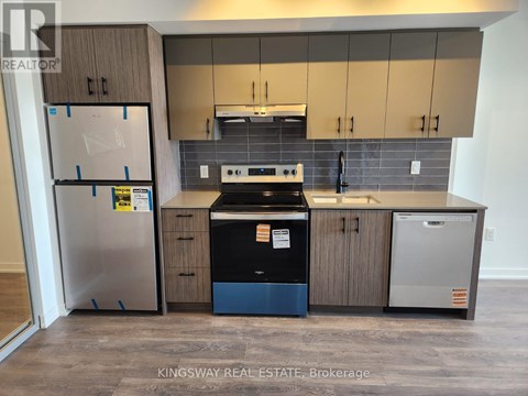 A kitchen with a refrigerator, oven, and cabinets.