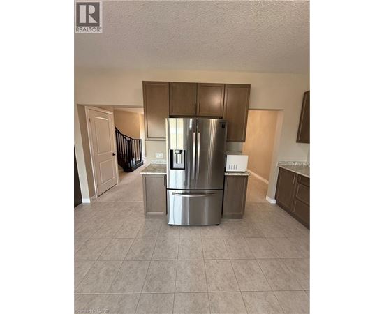 A kitchen with a stainless steel refrigerator and a tiled floor.