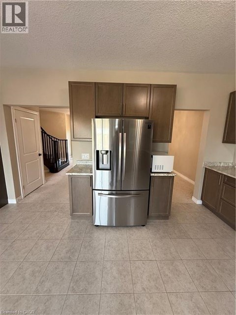 A kitchen with a stainless steel refrigerator and a tiled floor.