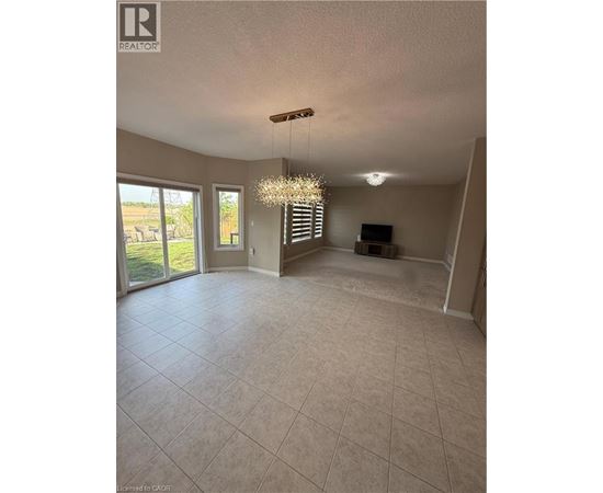 A spacious living room with a chandelier and sliding glass doors.