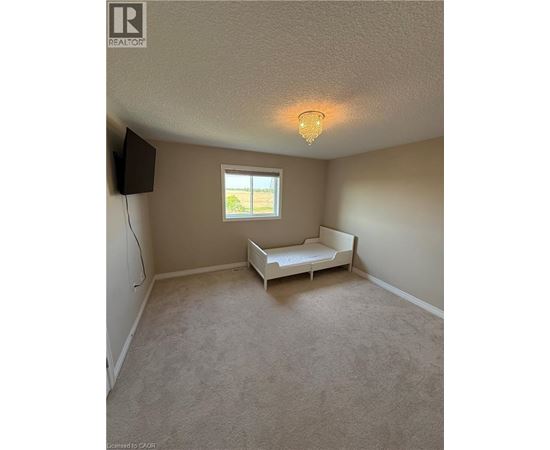 A bedroom with a bed, a window, and a chandelier.
