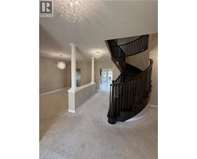 A spacious foyer with a staircase and a chandelier.
