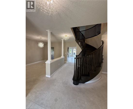 A spacious foyer with a staircase and a chandelier.