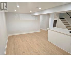 A spacious room with wooden flooring and white walls.
