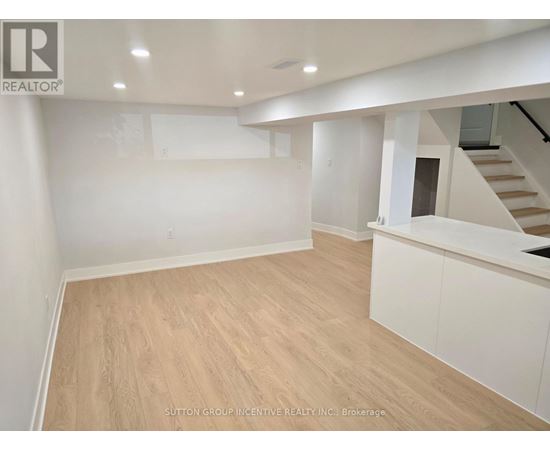 A spacious room with wooden flooring and white walls.
