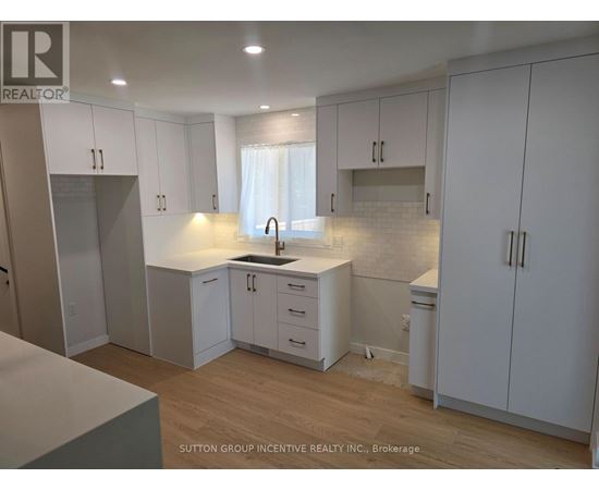 A kitchen with white cabinets and a wooden floor.