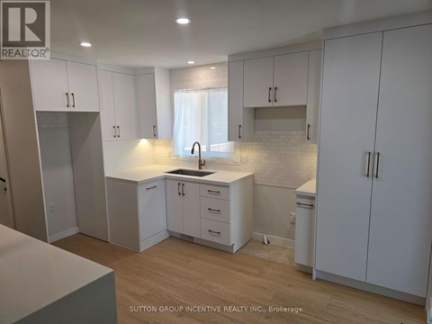 A kitchen with white cabinets and a wooden floor.