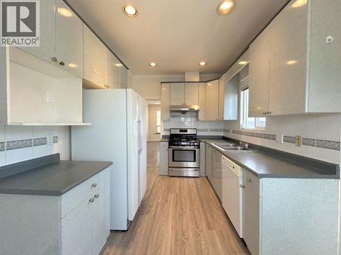 A modern kitchen with white cabinets and a wooden floor.