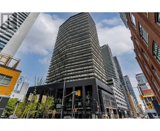 A tall building with a curved facade stands in front of other buildings.
