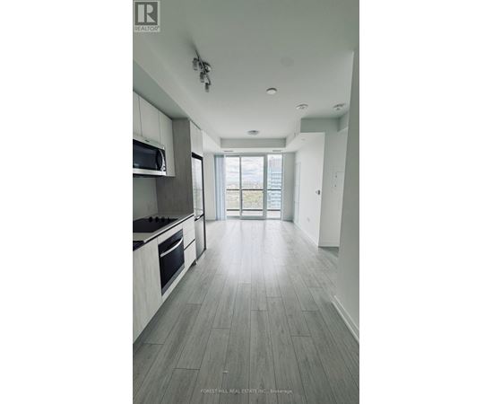 A spacious kitchen with a microwave above the stove and a view of the backyard through the open door.