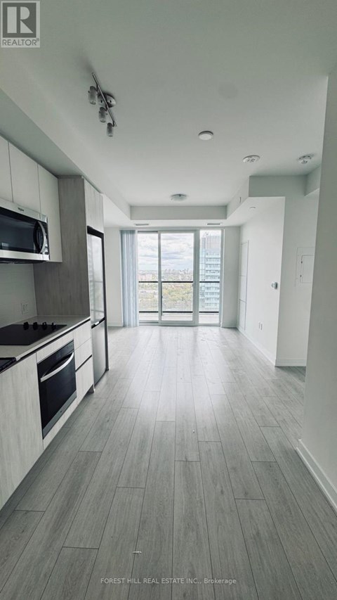 A spacious kitchen with a microwave above the stove and a view of the backyard through the open door.