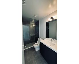 A modern bathroom with a toilet, sink, and mirror.