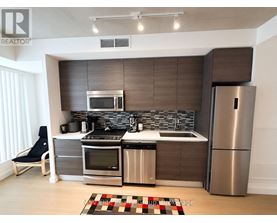 A modern kitchen with a refrigerator, oven, and sink.