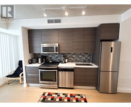 A modern kitchen with a refrigerator, oven, and sink.