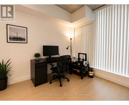 A room with a desk, chair, and a plant.