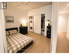 A bedroom with a bed, nightstand, and a closet with a mirror.