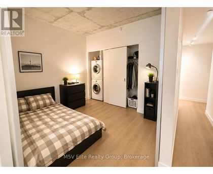 A bedroom with a bed, nightstand, and a closet with a mirror.