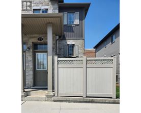 A grey house with a white fence in front.