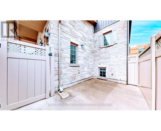 A white gate is closed on a stone wall.