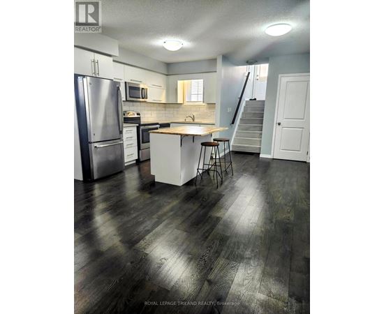 A kitchen with a refrigerator, stove, and bar stools.
