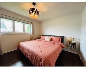 A bedroom with a pink bedspread and a black lamp.