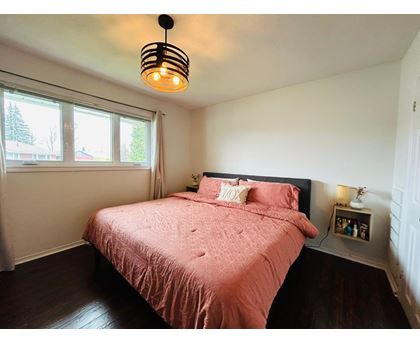 A bedroom with a pink bedspread and a black lamp.