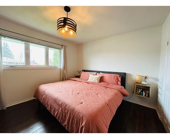 A bedroom with a pink bedspread and a black lamp.