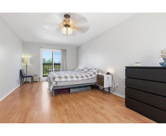 A bedroom with a bed, dresser, and window.