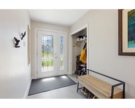 A hallway with a bench and a door with a glass window.