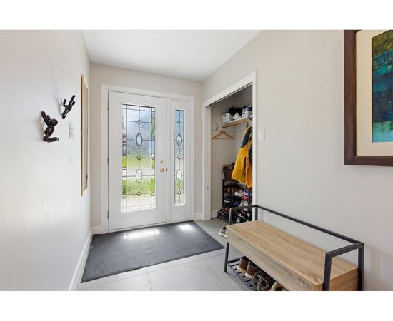 A hallway with a bench and a door with a glass window.