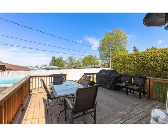 A wooden deck with a table and chairs overlooking a pool.
