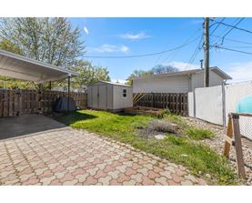 A backyard with a paved walkway and a fence.