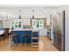 A kitchen with a blue island and stools.