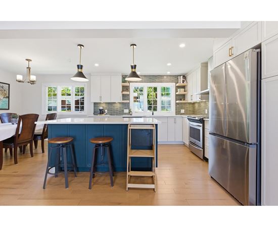 A kitchen with a blue island and stools.