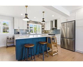 A kitchen with a blue backsplash and white cabinets.