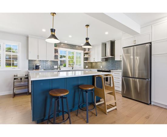 A kitchen with a blue backsplash and white cabinets.