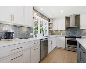 A modern kitchen with white cabinets and stainless steel appliances.