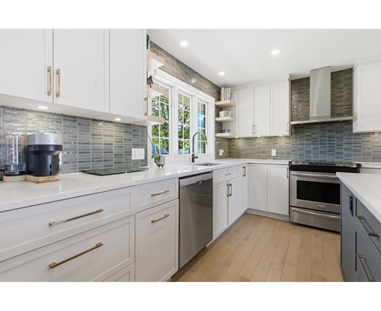 A modern kitchen with white cabinets and stainless steel appliances.