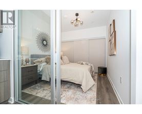 A bedroom with a bed, nightstand, and a wall hanging.