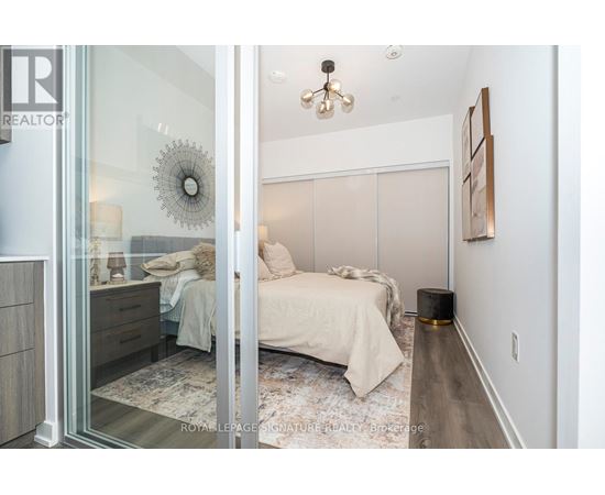 A bedroom with a bed, nightstand, and a wall hanging.