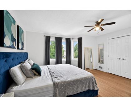 A bedroom with a large bed and a ceiling fan.
