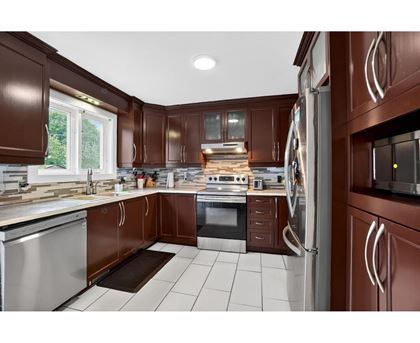 A kitchen with brown cabinets and a white tiled floor.